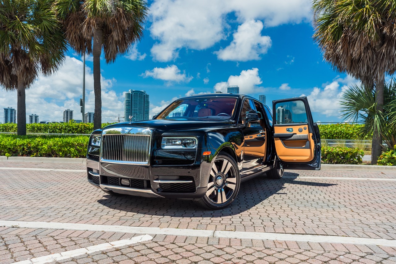 Rolls-Royce Cullinan preto da frota, com as portas abertas e os prédios de Miami ao fundo.