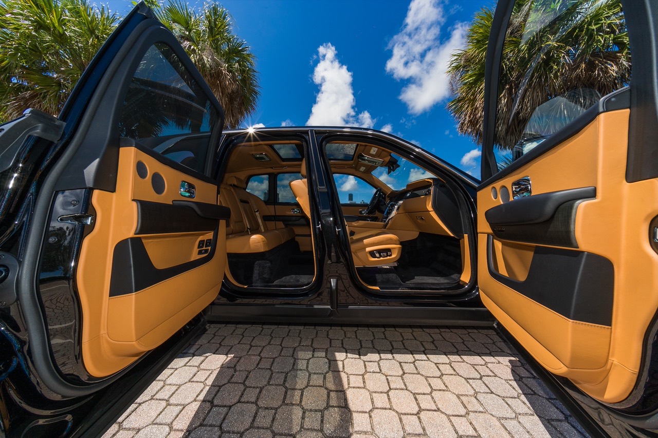 Rolls-Royce Cullinan da frota com as portas abertas e o interior de couro caramelo.